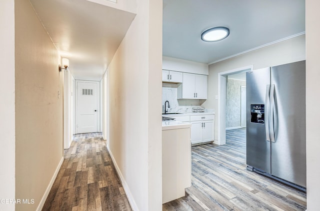 corridor with a sink, light wood-style floors, and baseboards
