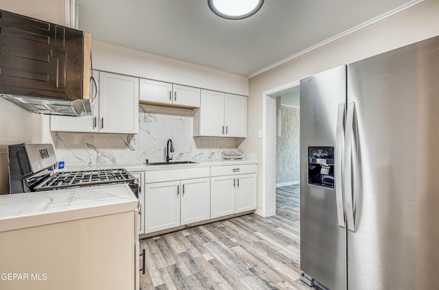 kitchen with appliances with stainless steel finishes, a sink, light wood-style flooring, light countertops, and tasteful backsplash
