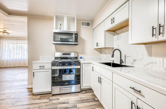kitchen featuring stainless steel appliances, a sink, light wood-style floors, light countertops, and white cabinets