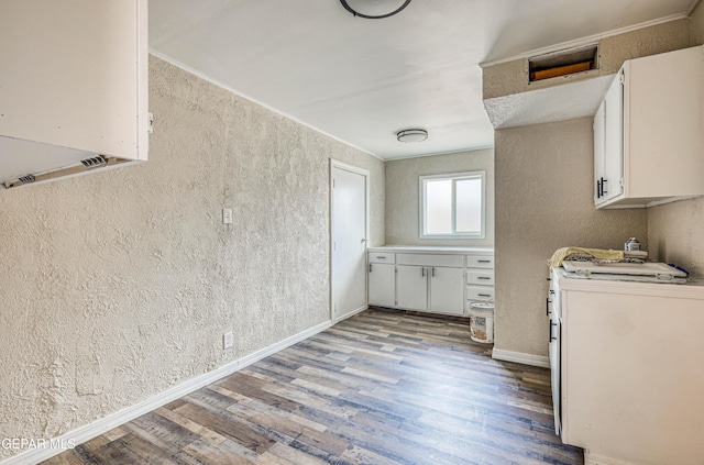 kitchen featuring wood finished floors, white cabinetry, a textured wall, light countertops, and baseboards