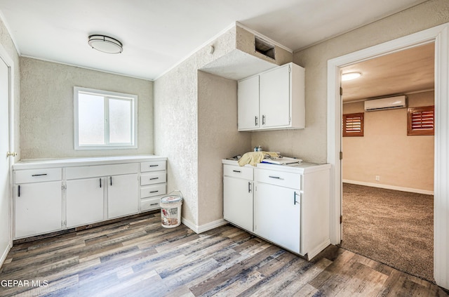 laundry room featuring a wall mounted AC, wood finished floors, a textured wall, and baseboards