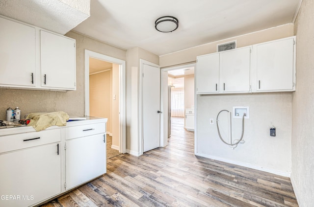 kitchen with light wood-style flooring, white cabinetry, light countertops, and baseboards