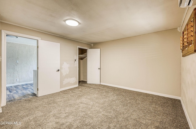unfurnished bedroom with carpet, a closet, baseboards, and a wall unit AC