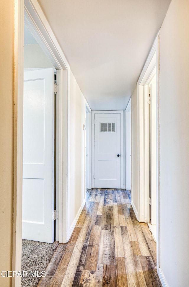 corridor with wood finished floors and baseboards