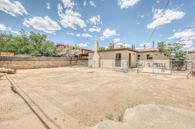 rear view of property featuring stucco siding, a fenced backyard, and a gate
