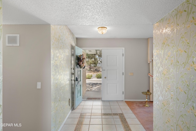 foyer with wallpapered walls, baseboards, a textured ceiling, and light tile patterned flooring