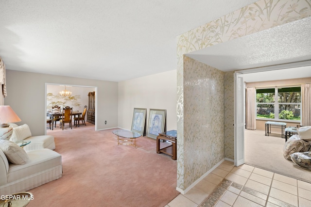 living room featuring a textured ceiling, carpet flooring, a chandelier, baseboards, and tile patterned floors