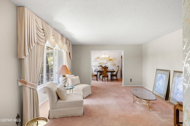 living area with light colored carpet, a chandelier, a textured ceiling, and baseboards