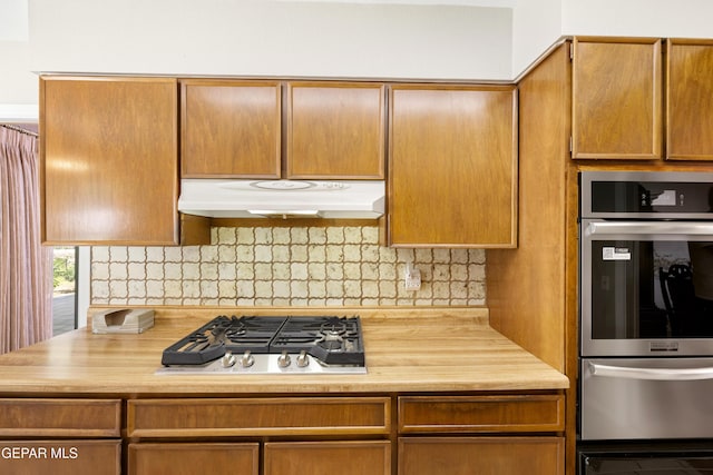 kitchen with stainless steel appliances, under cabinet range hood, a warming drawer, and backsplash