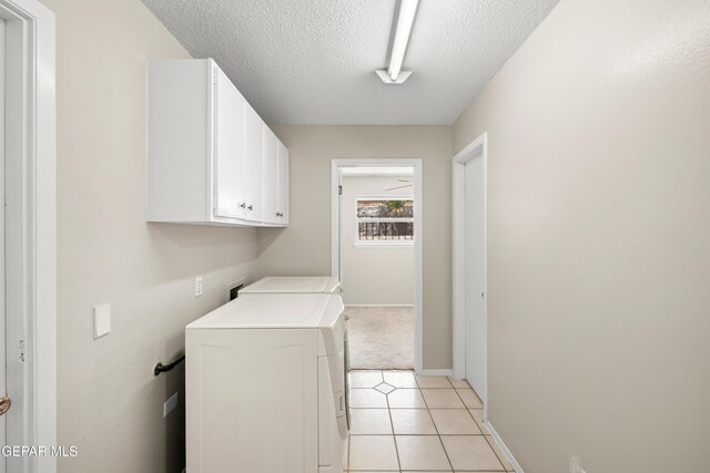 laundry room with cabinet space, washer and clothes dryer, a textured ceiling, baseboards, and light tile patterned floors