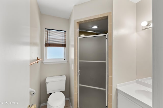 bathroom with a stall shower, toilet, vanity, and baseboards