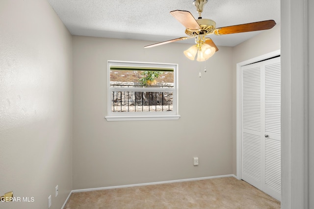 unfurnished bedroom with light colored carpet, a closet, baseboards, and a ceiling fan
