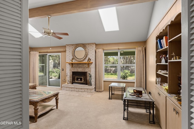 carpeted living room with ceiling fan, a brick fireplace, and a skylight