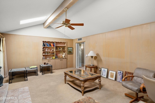 carpeted living room featuring a ceiling fan, wood walls, and a skylight
