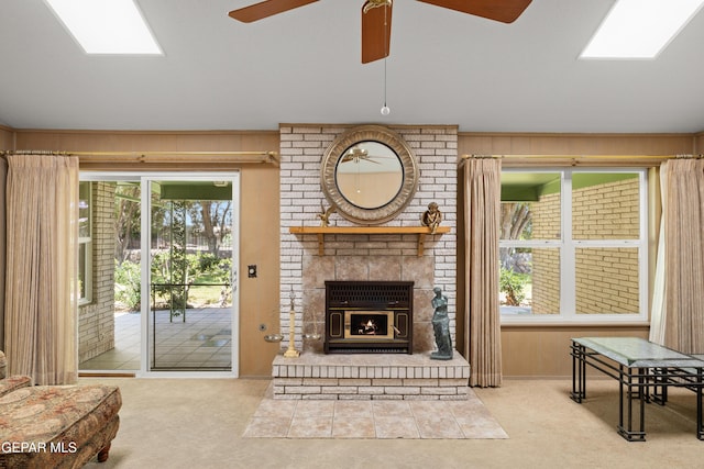 living room with carpet floors, a ceiling fan, a brick fireplace, healthy amount of natural light, and wood walls
