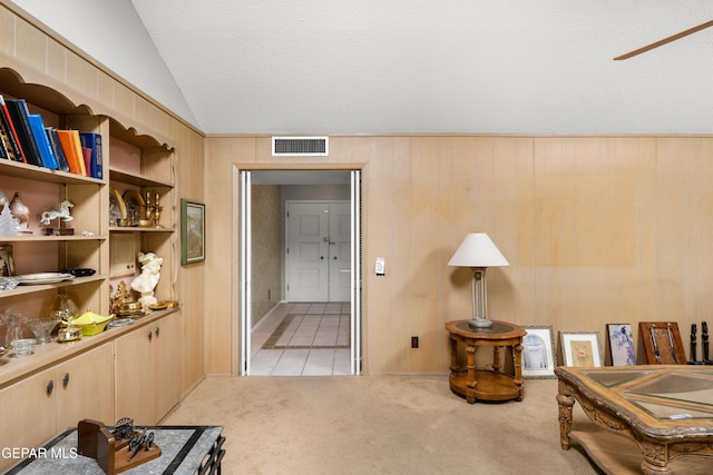 living area featuring lofted ceiling, light colored carpet, a textured ceiling, and light tile patterned floors