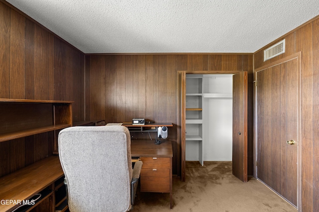 office area featuring wooden walls, light carpet, and a textured ceiling