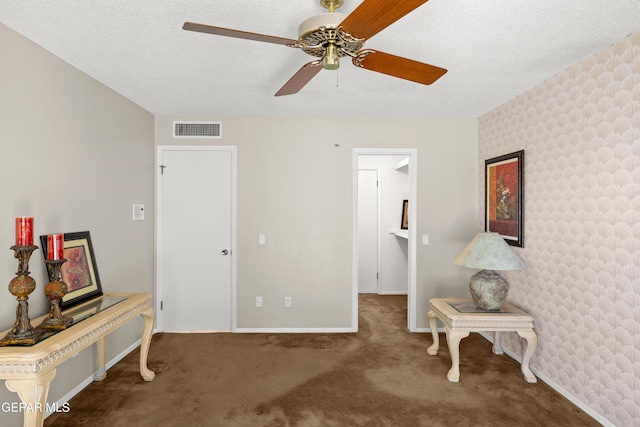 sitting room with carpet, a ceiling fan, baseboards, a textured ceiling, and wallpapered walls