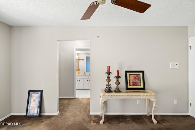 corridor with carpet flooring, a textured ceiling, baseboards, and a sink