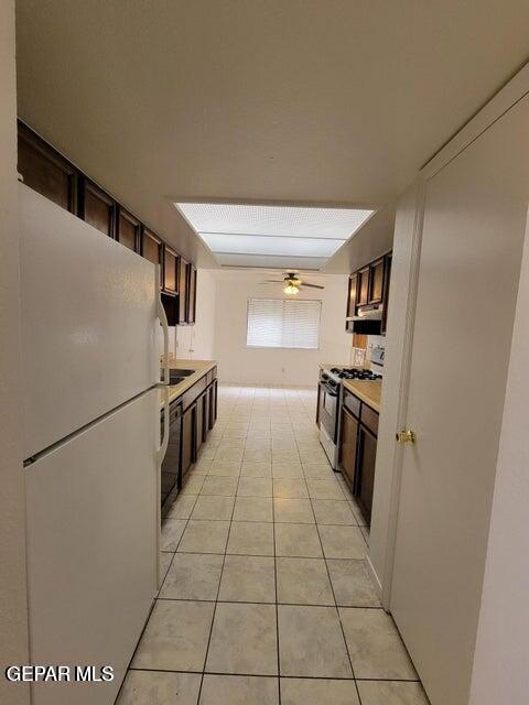 7716 Iroquois Dr, El Paso, TX 79912 - kitchen featuring freestanding refrigerator, gas stove, light countertops, dark brown cabinets, and light tile patterned floors