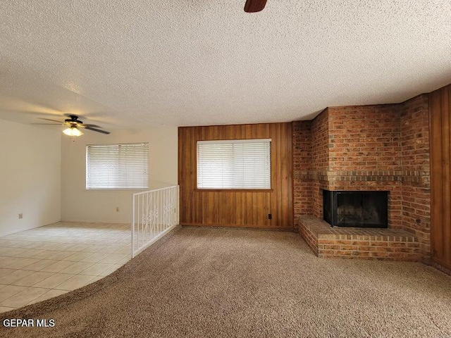 7716 Iroquois Dr, El Paso, TX 79912 - unfurnished living room featuring ceiling fan, a textured ceiling, a fireplace, wooden walls, and tile patterned flooring