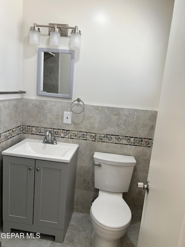 6044 Cabrillo Dr, El Paso, TX 79912 - half bath with toilet, tile walls, vanity, wainscoting, and tile patterned flooring