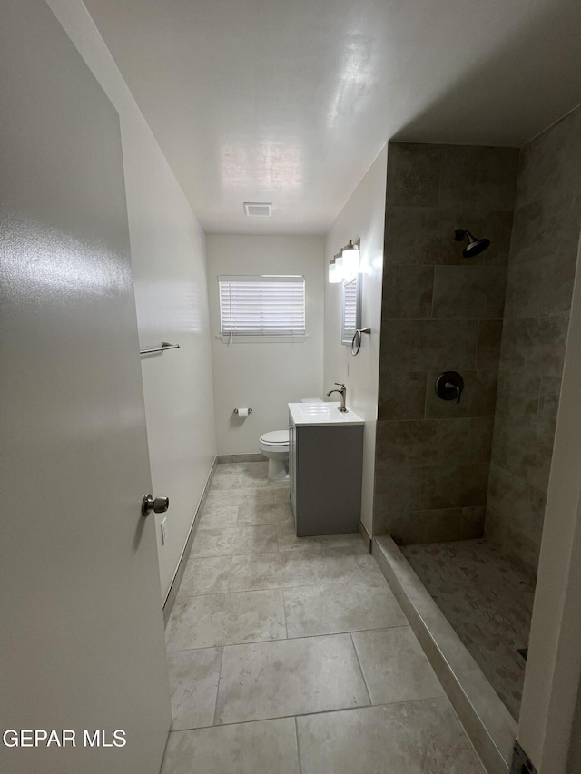 6044 Cabrillo Dr, El Paso, TX 79912 - bathroom with tiled shower, vanity, toilet, baseboards, and tile patterned floors