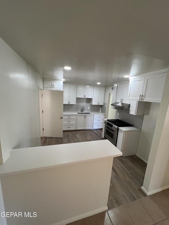 6044 Cabrillo Dr, El Paso, TX 79912 - kitchen with gas stove, a sink, under cabinet range hood, white cabinets, and recessed lighting