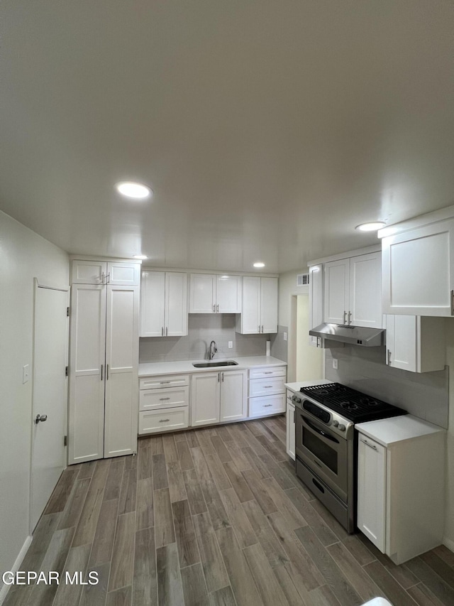 6044 Cabrillo Dr, El Paso, TX 79912 - kitchen with stainless steel gas range, wood finish floors, white cabinetry, under cabinet range hood, and recessed lighting