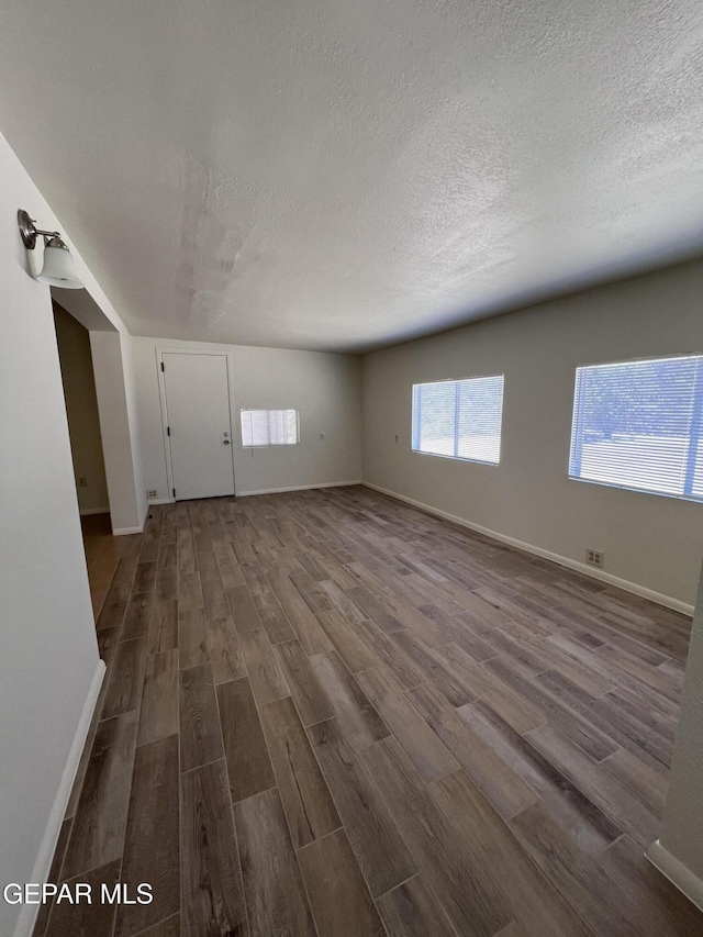 6044 Cabrillo Dr, El Paso, TX 79912 - spare room featuring dark wood finished floors, a textured ceiling, and baseboards