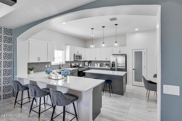 10705 Troy Aikman Dr, El Paso, TX 79924 - kitchen with stainless steel appliances, a breakfast bar area, a peninsula, light countertops, and white cabinets