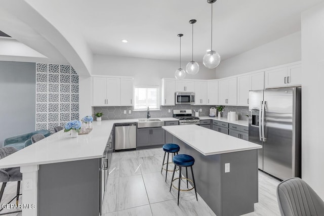 10705 Troy Aikman Dr, El Paso, TX 79924 - kitchen featuring appliances with stainless steel finishes, a sink, a kitchen bar, gray cabinetry, and tasteful backsplash