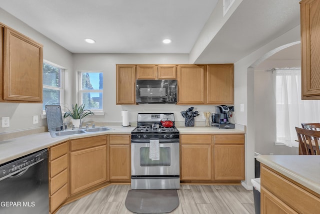 12572 Paseo Alegre Dr, El Paso, TX 79928 - kitchen featuring black appliances, a sink, light countertops, light wood-style flooring, and arched walkways
