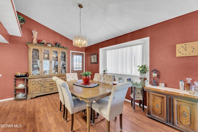 12273 El Greco Cir, El Paso, TX 79936 - dining room with a textured wall, a chandelier, a textured ceiling, lofted ceiling, and light wood finished floors
