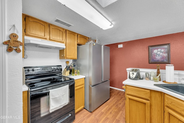 12273 El Greco Cir, El Paso, TX 79936 - kitchen featuring black electric range, under cabinet range hood, freestanding refrigerator, light wood-style flooring, and light countertops
