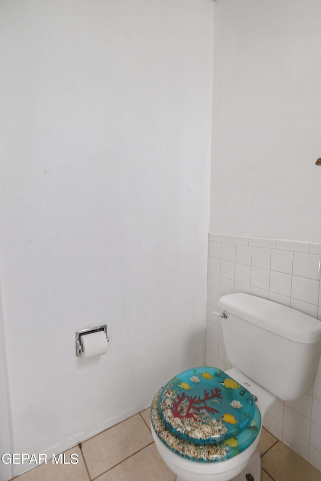 bathroom with tile patterned floors, toilet, and tile walls