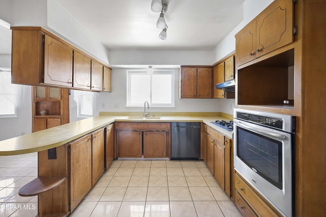 kitchen with dishwashing machine, oven, a sink, a peninsula, and brown cabinetry