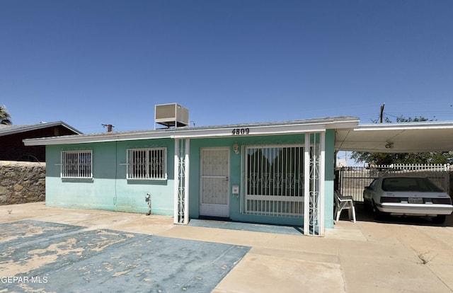 view of front of home featuring fence, a carport, and central air condition unit