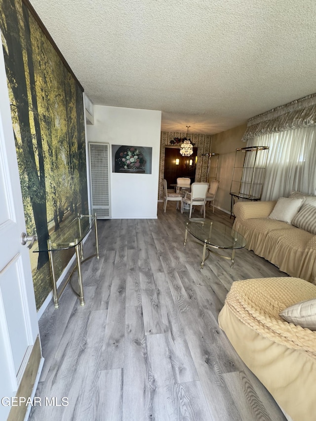 living area with a textured ceiling, a chandelier, and wood finished floors