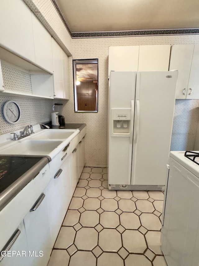 kitchen with white refrigerator with ice dispenser, white cabinets, range, a sink, and light floors