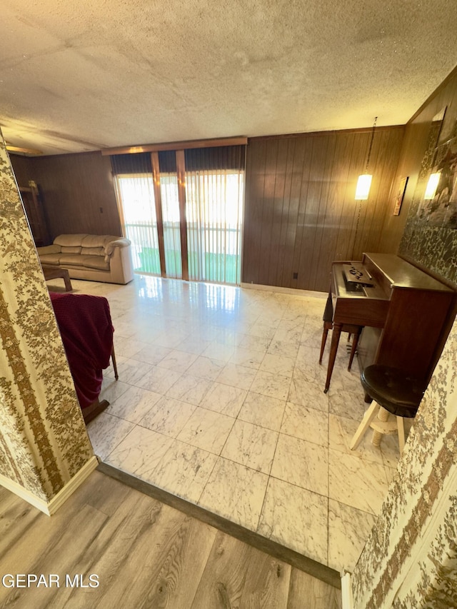 living room featuring wood walls, a textured ceiling, and marble look tile flooring