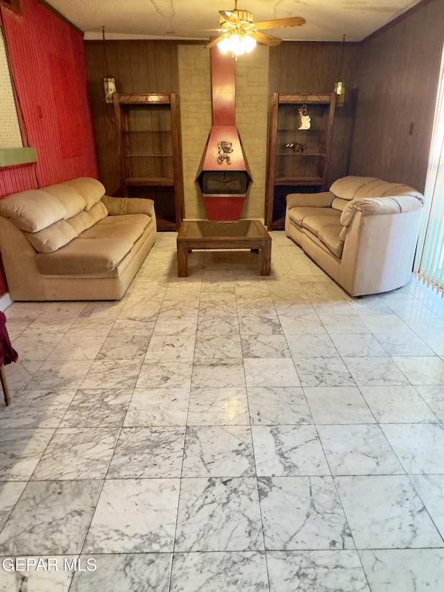 living room with wooden walls, marble finish floors, ceiling fan, and a wood stove