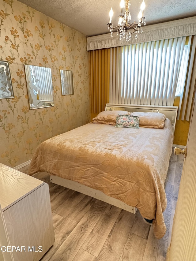 bedroom featuring wood finished floors, a chandelier, and a textured ceiling