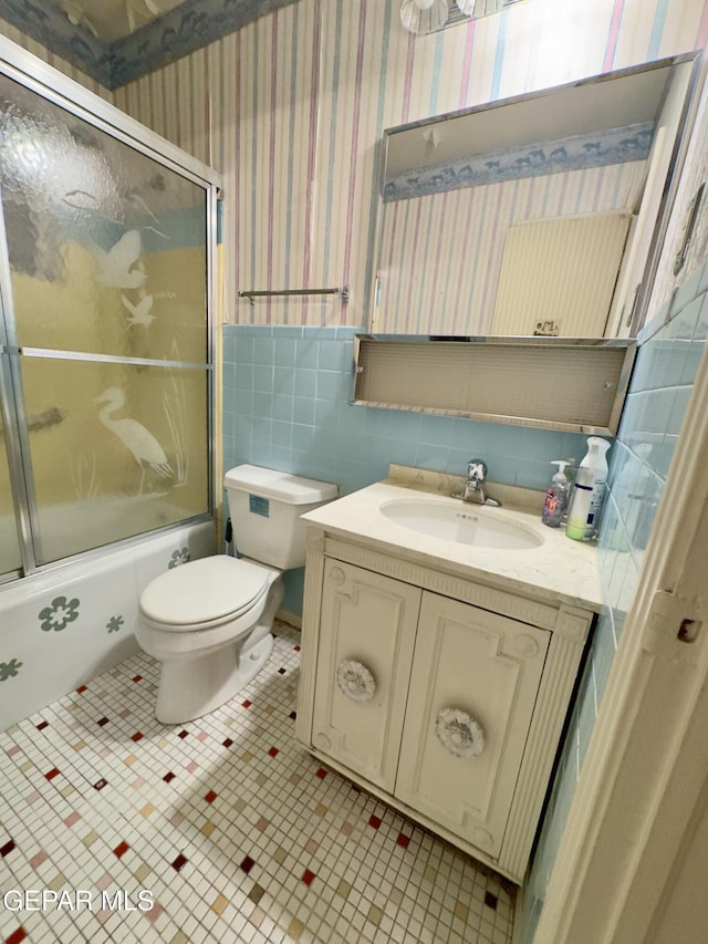 bathroom featuring wallpapered walls, bath / shower combo with glass door, toilet, and vanity