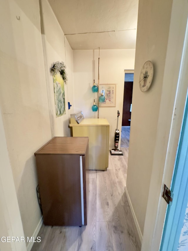 hall with washer / clothes dryer, light wood-style flooring, and baseboards