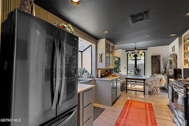 1114 Los Jardines Cir, El Paso, TX 79912 - kitchen featuring freestanding refrigerator, stainless steel gas stove, light wood finished floors, light countertops, and glass insert cabinets