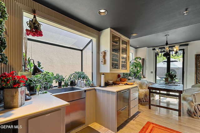 1114 Los Jardines Cir, El Paso, TX 79912 - kitchen featuring light wood finished floors, light countertops, glass insert cabinets, stainless steel dishwasher, and a chandelier