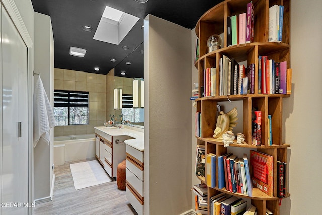 1114 Los Jardines Cir, El Paso, TX 79912 - bathroom featuring a skylight, wood finished floors, a bath, and vanity