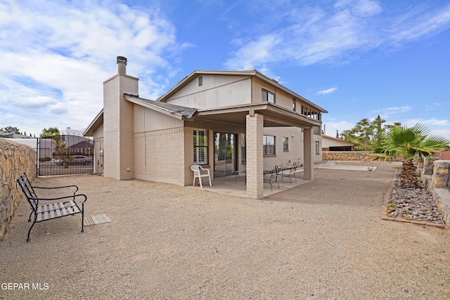 1393 Vista Granada Dr, El Paso, TX 79936 - rear view of property featuring a chimney, a patio area, fence, brick siding, and a gate