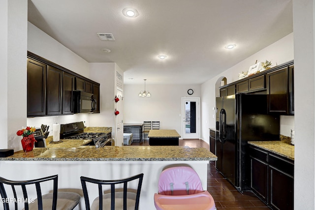 kitchen featuring black appliances, dark brown cabinets, a peninsula, a kitchen breakfast bar, and recessed lighting